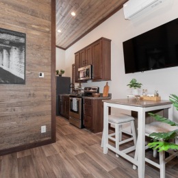 a kitchen with dark wood accents seating table and a tv