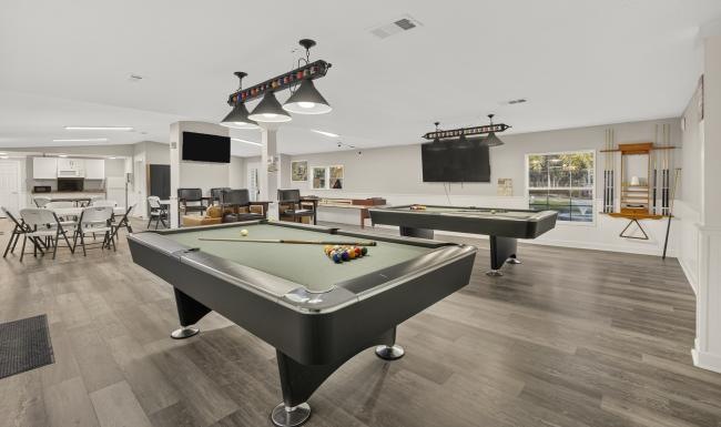 a clubroom with pool tables and chairs